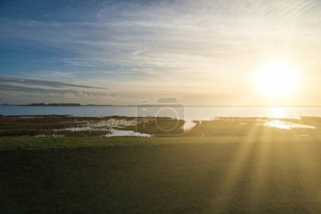 Foto de Puesta de sol en el Bodden en Zingst en la península del Mar Báltico. Paisaje bodden con prados. Reserva natural en la costa. Fotografía del paisaje - Imagen libre de derechos