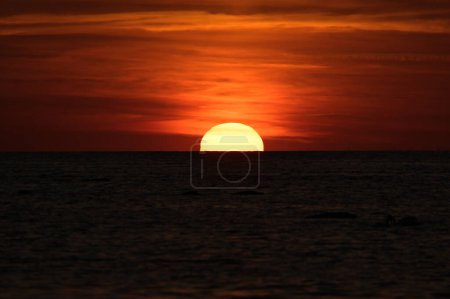 Puesta de sol en el horizonte del Mar Báltico. Ambiente romántico por la noche junto al mar. El sol naranja se hunde en el agua. Paisaje foto