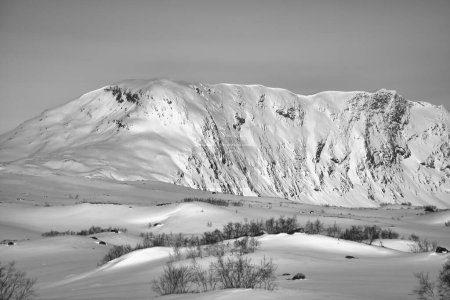 Norwegian high mountains in the snow. Mountains covered with snow in black and white. Snowy landscape in Scandinavia