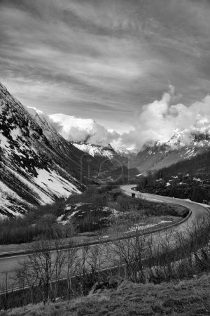 Norwegian landscape. The road leads through a mountain gorge that descends from the glacier. Rough nature in Scandinavia. Landscape photo from the north