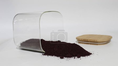 Photo for Aronia berries powder spilled from a jar. - Royalty Free Image