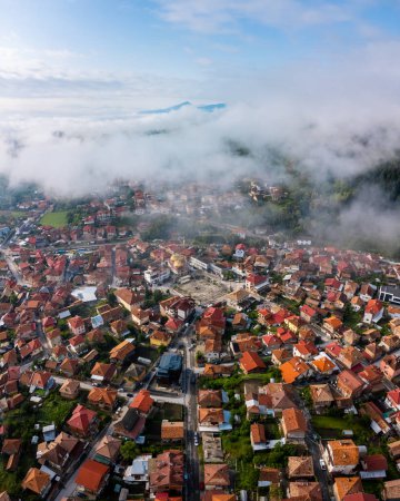 Bulgaria - 05 22 2024: Epic drone shot using the Mini 2 capturing the beautiful morning light with vibrant blue sky and foggy horizon over the village and the forest, with the beautiful golden mosque.