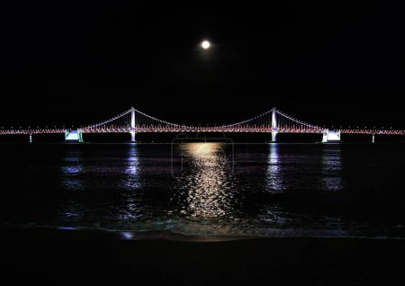 Photo for Busan, South Korea - May 2019: Busan Gwangan bridge taken from Gwangalli beach in night time with moon - Royalty Free Image