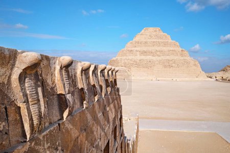 Foto de Saqqara, Egipto - 2 de enero de 2024: La Pirámide de Djoser (o Djeser y Zoser), o Pirámide de Paso y la pared de cobra de la necrópolis de Saqqara - Imagen libre de derechos