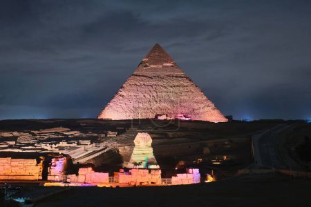Foto de Giza, Egipto - 24 de diciembre de 2023: Esfinge y pirámide de Khafre (Kefren) en la meseta de Giza, El Cairo en las luces nocturnas - Imagen libre de derechos