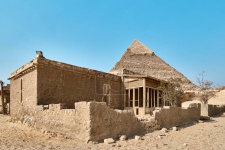 Foto de Giza, Egipto - 24 de diciembre de 2023: Pirámide de Khafre (también conocida como Khafra, Khefren) en la meseta de Giza, y antigua casa de adobe - Imagen libre de derechos