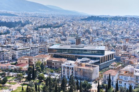 Photo for Athens, Greece - March 03, 2024: View of Acropolis Archaeological Museum designed by Bernard Tschumi and athens ciyscape from acropolis hill - Royalty Free Image