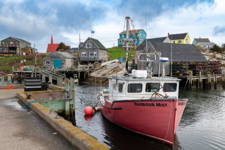Peggy's Cove, Nova Scotia, Canada - October 23, 2023: A fishing boat in the harbor with the houses on the background, in the fishing village of Peggy's Cove, in Southern Nova Scotia, Canada.
