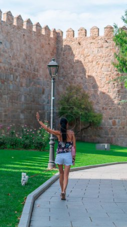 Téléchargez les photos : Jeune femme détendue debout à l'extérieur, profitant de vacances et de loisirs contre un beau mur architectural - en image libre de droit
