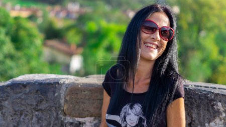 Téléchargez les photos : Femme souriante en lunettes à la mode et vêtements décontractés en plein air - en image libre de droit