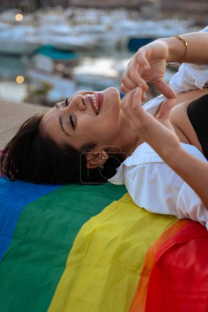 Smiling young woman with lgtbi flag fighting and showing strength out of pride. Concept: lifestyle, pride, outdoors