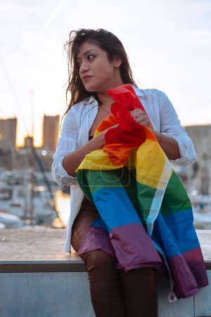 Smiling young woman with lgtbi flag fighting and showing strength out of pride. Concept: lifestyle, pride, outdoors