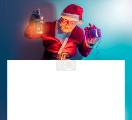 Photo for Santa Claus holding white blank banner or copy space for text, Merry Christmas and New Year's Eve concept - Royalty Free Image
