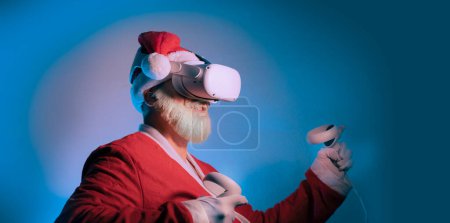 Photo pour Santa porter vr casque gadget appareil équipement regarder l'expérience réaliste. Les personnes âgées moustache aux cheveux gris barbu Père Noël l'expérience de la réalité virtuelle jouer dans le jeu vidéo - image libre de droit