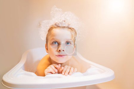 Téléchargez les photos : Drôle petit garçon de cinq ans assis dans la baignoire - en image libre de droit