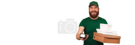 Photo for Delivery man wearing cap has brought you ordered boxes and holds pos terminal. Studio portrait over white background. - Royalty Free Image