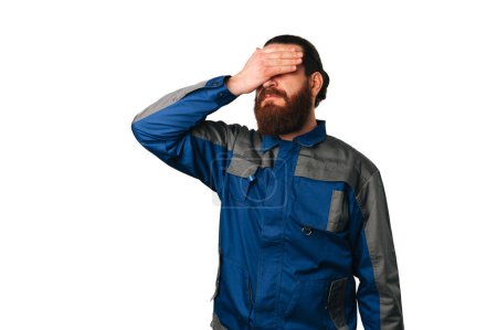 Téléchargez les photos : Disappointed man wearing handyman uniform is and makes facepalm gesture. Portrait over white background. - en image libre de droit