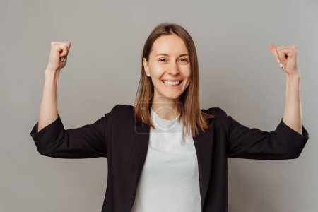Photo for Photo of cheerful young woman celebrating victory over grey background. - Royalty Free Image
