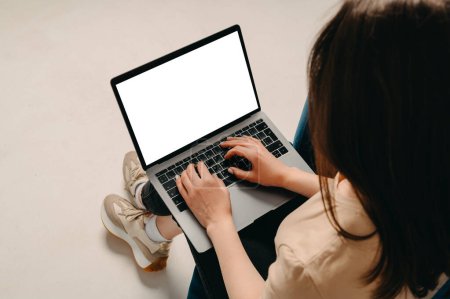 Studio sans visage tourné de jeune femme à l'aide de son ordinateur portable avec écran blanc avec espace de copie.