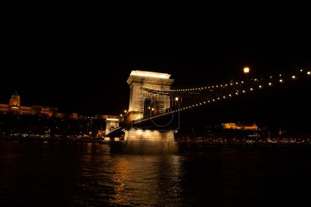 La nuit révèle une vue fascinante d'un pont illuminé et réfléchissant sur une rivière sombre dans un paysage urbain