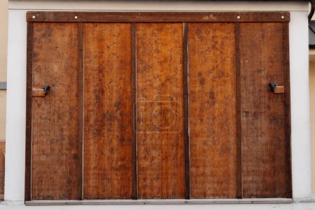 A rustic wooden sliding barn door is shown mounted on a white wall, highlighting its natural texture in a closeup view