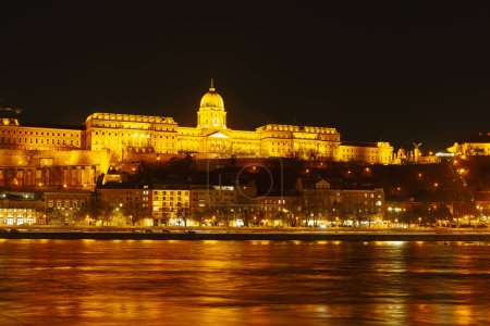 Ein prachtvolles historisches Gebäude leuchtet in der Nacht, spiegelt sich in einem ruhigen Fluss und bildet einen atemberaubenden Blick