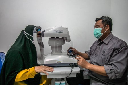 Photo for BOGOR, INDONESIA - March 27, 2023: A resident carries out an eye test using a Specular Microscope at the Ainun Cahaya Medika eye clinic, Bogor Regency District, Indonesia, on March 27, 2023 - Royalty Free Image