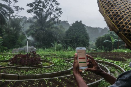 Photo for BOGOR, INDONESIA - February 18, 2022: Farmers in Bogor, West Java, Indonesia, use technology to water their plants using cell phones that can be operated from anywhere - Royalty Free Image