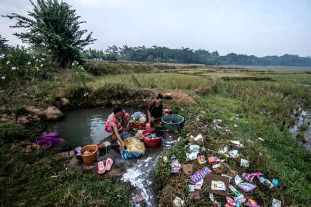 Foto de Bogor, Indonesia - 12 de agosto de 2023: Los residentes en Bogor, Java Occidental, se vieron obligados a usar agua de infiltración en el arrozal para lavar la ropa debido a la escasez de agua limpia causada por una sequía - Imagen libre de derechos