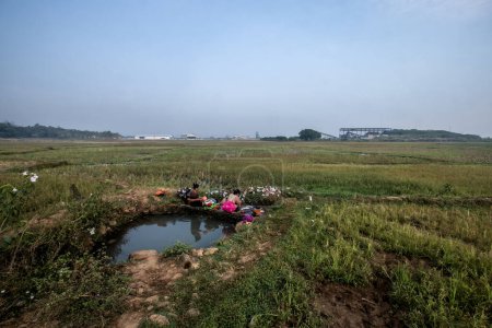 Photo for Bogor, Indonesia - August 12, 2023: Residents in Bogor, West Java, were forced to use infiltration water in the paddy field to wash clothes due to the scarcity of clean water caused by a drought - Royalty Free Image