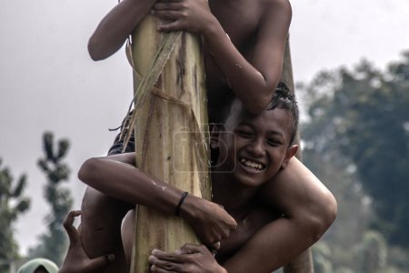Photo for Bogor, Indonesia - August 17, 2023: Children race to collect hanging prizes by climbing a tree trunk covered with lubricant at the 78th Indonesian Independence Day celebration in Bogor, West Java, Indonesia, on August 17, 2023 - Royalty Free Image
