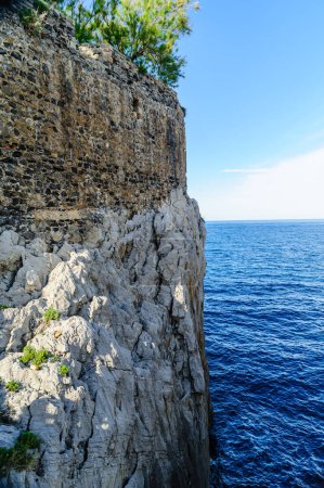 Téléchargez les photos : Le phare historique de Castro Urdiales, qui fait partie d'un ancien château, se dresse sur une falaise escarpée sur fond de ciel dégagé - en image libre de droit