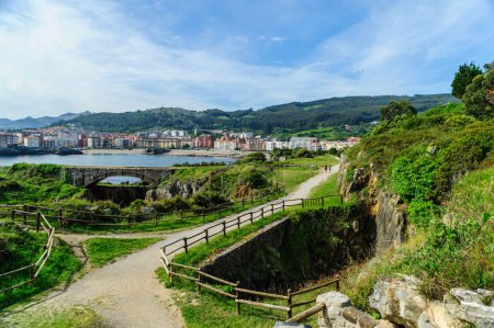 Téléchargez les photos : Un sentier pédestre pittoresque le long de la côte rocheuse avec vue sur la ville de Castro Urdiales et des collines luxuriantes en arrière-plan. - en image libre de droit