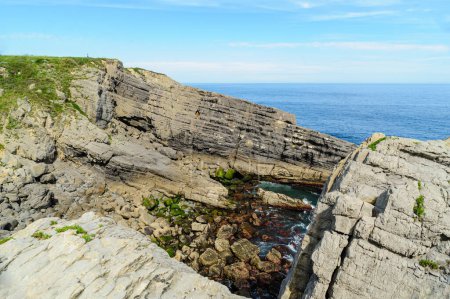 Téléchargez les photos : Des formations rocheuses en couches frappantes le long de la côte accidentée du nord de l'Espagne avec un ciel bleu clair au-dessus. - en image libre de droit