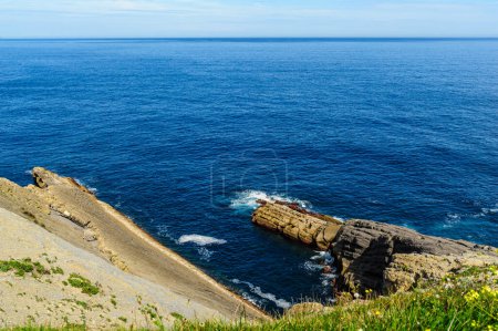 Téléchargez les photos : Des formations rocheuses en couches frappantes le long de la côte accidentée du nord de l'Espagne avec un ciel bleu clair au-dessus. - en image libre de droit