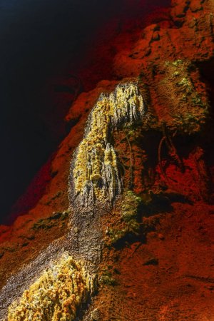 Sulfuric sediment and vibrant iron-rich deposits along the dark waters of the Rio Tinto river