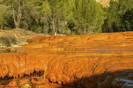 The setting sun casts a warm glow on the rust-colored terraced mineral deposits along Rio Tinto