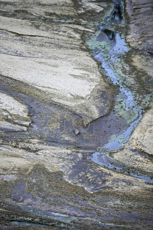 Naturally striated rock formations with traces of blue-green acidic water in the Rio Tinto region