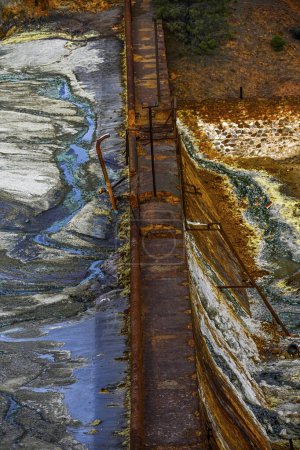 Téléchargez les photos : The vibrant orange hues of an acidic stream contrast with a stone wall in the historical Rio Tinto mining area - en image libre de droit
