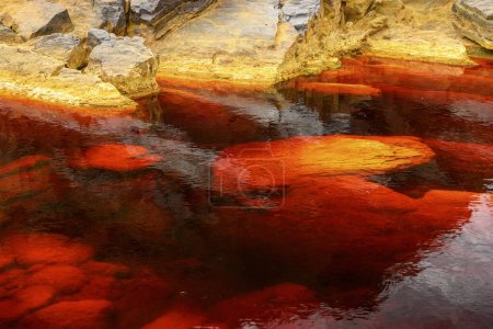 The otherworldly red waters of Rio Tinto flow beside steep rocky cliffs, highlighting nature's unique artistry.
