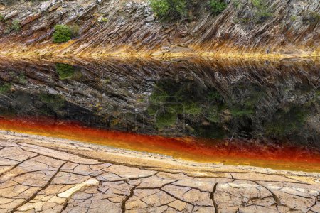 Des couches de terre frappantes et une traînée vive d'eau rouge tapissent le sol fissuré du Rio Tinto