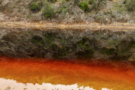 Capas impactantes de tierra y una veta vívida de agua roja alinean el suelo agrietado del Río Tinto