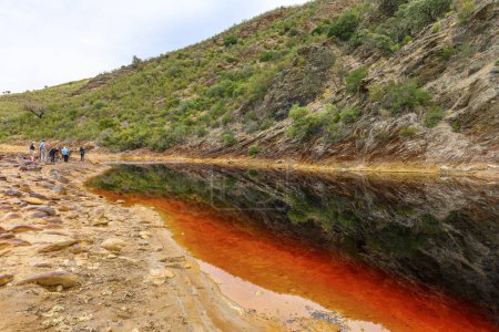 Striking layers of earth and a vivid streak of red water line the cracked ground of the Rio Tinto