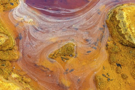 Téléchargez les photos : Des couches de terre frappantes et une traînée vive d'eau rouge tapissent le sol fissuré du Rio Tinto - en image libre de droit