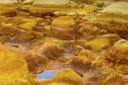 Photo for The warm, orange mineral deposits of Rio Tinto sculpt a textured landscape with reflective puddles - Royalty Free Image