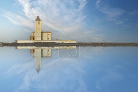 A beautiful church reflects on the glassy surface of water under the vast sky at Cabo de Gata