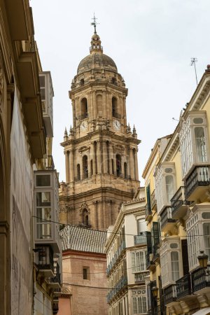 The iconic bell tower of Malaga Cathedral rises majestically between traditional Spanish buildings in the heart of the city.
