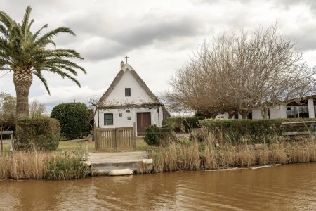 A charming thatched-roof cottage stands by the water's edge in Albufera Natural Park near Valencia, offering a peaceful rural retreat.