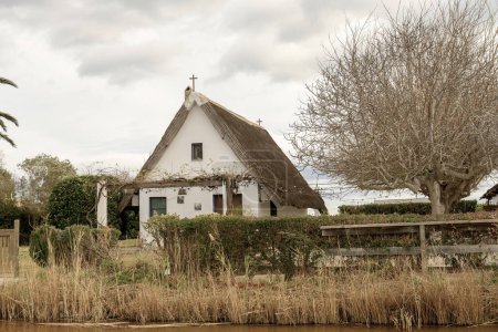 Photo for A charming thatched-roof cottage stands by the waters edge in Albufera Natural Park near Valencia, offering a peaceful rural retreat. - Royalty Free Image