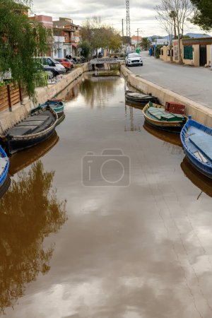 Photo for Traditional wooden boats moored along a canal, with the rustic charm of Albufera Valencias township lining the shores - Royalty Free Image